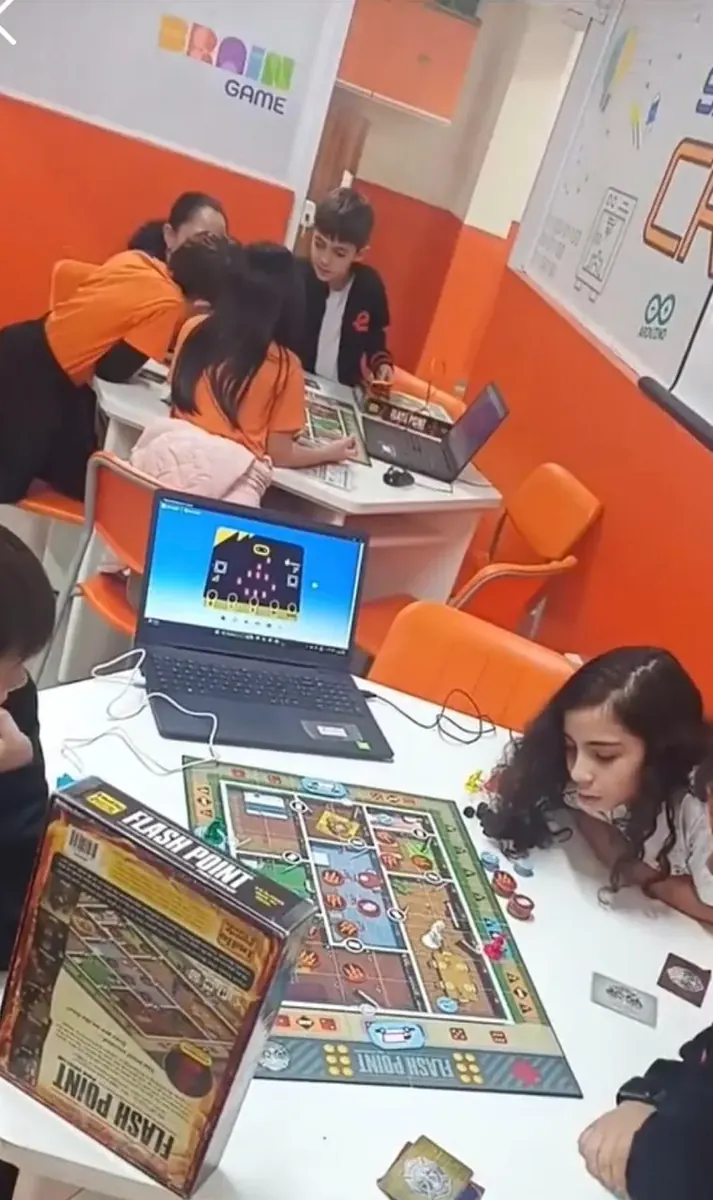 Sala do Brain Game: turmas divididas entre jogos de tabuleiro e programação em notebooks