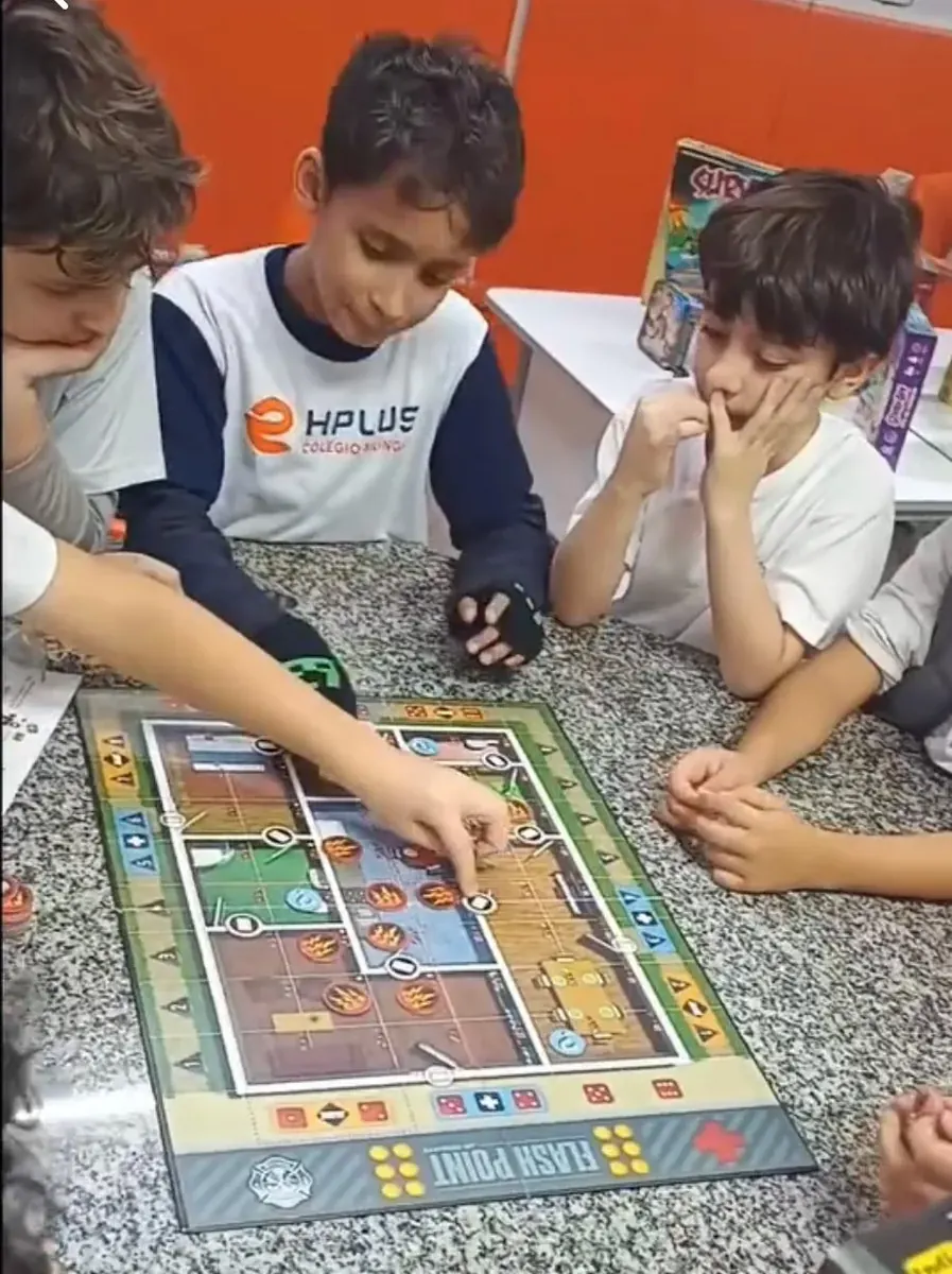 Três alunos do COLÉGIO HPLUS concentrados num jogo de tabuleiro cooperativo na aula de Brain Game