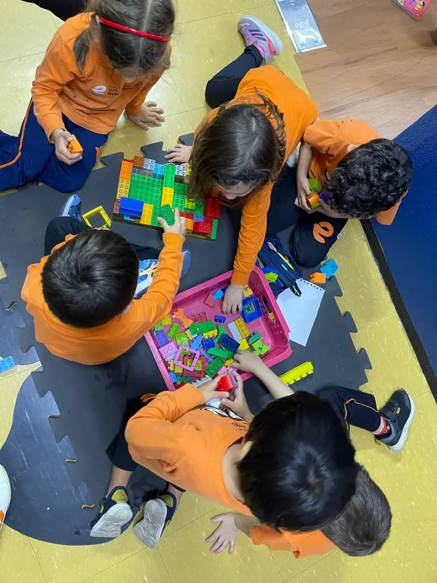 Crianças da Educação Infantil montando blocos de encaixe no chão da sala