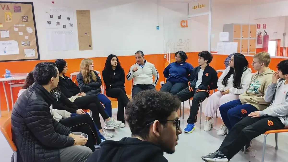 Turma do Ensino Médio sentada em roda ouvindo um profissional convidado numa conversa sobre carreira