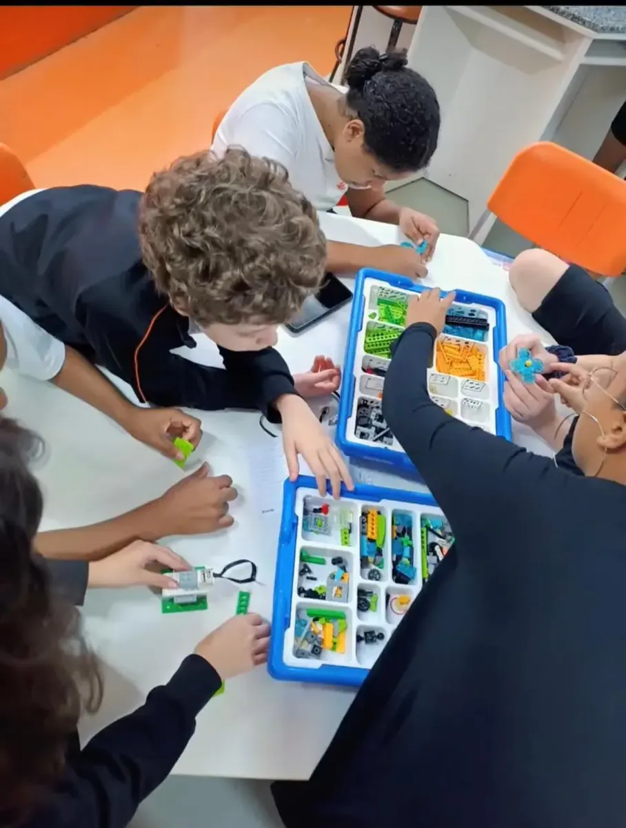 Alunos do COLÉGIO HPLUS montando um projeto de robótica com kit de peças e placa programável